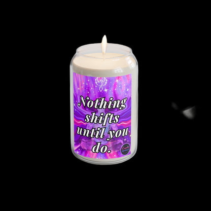 Candle with a motivational label on a white surface with a plant and watch in the background